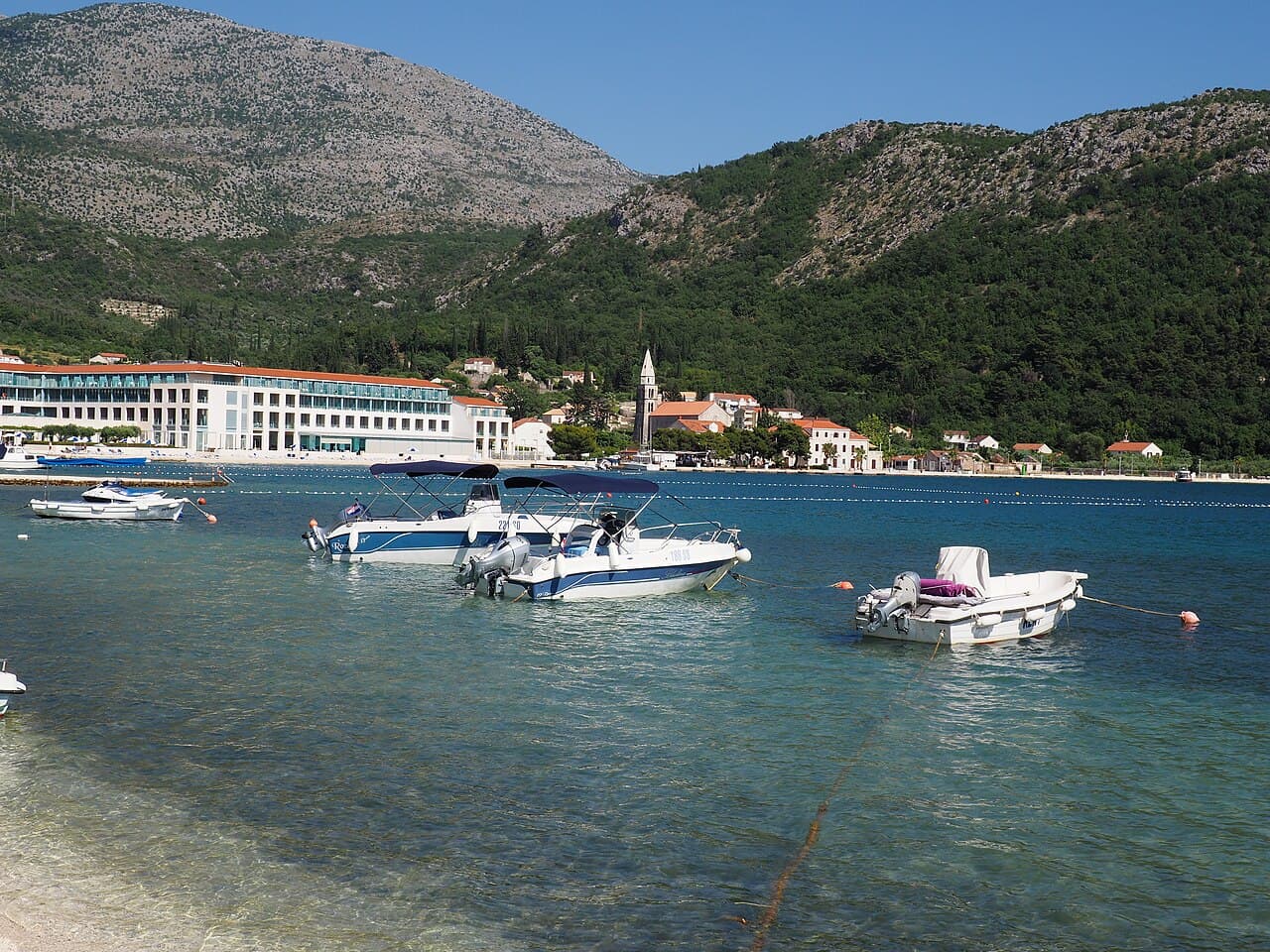 Boats in the calm bay of Slano with the bell tower behind