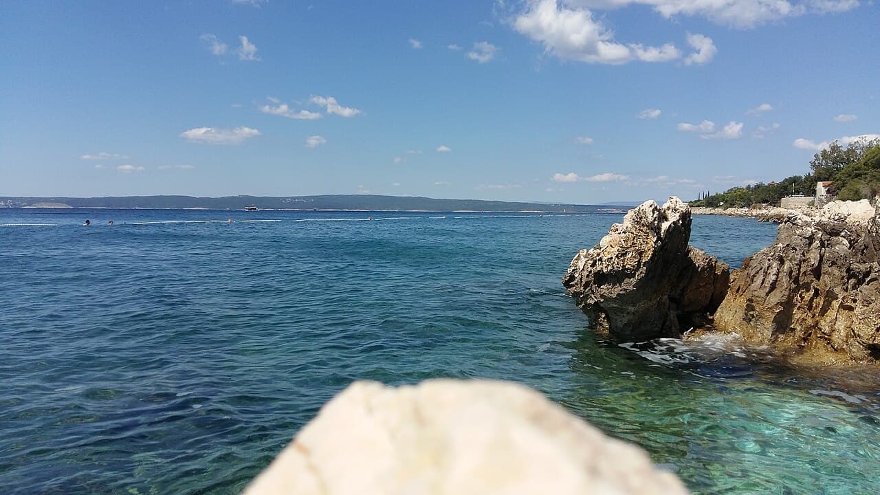Rocky coast and clear sea at Novi Vinodolski with islands on the horizon