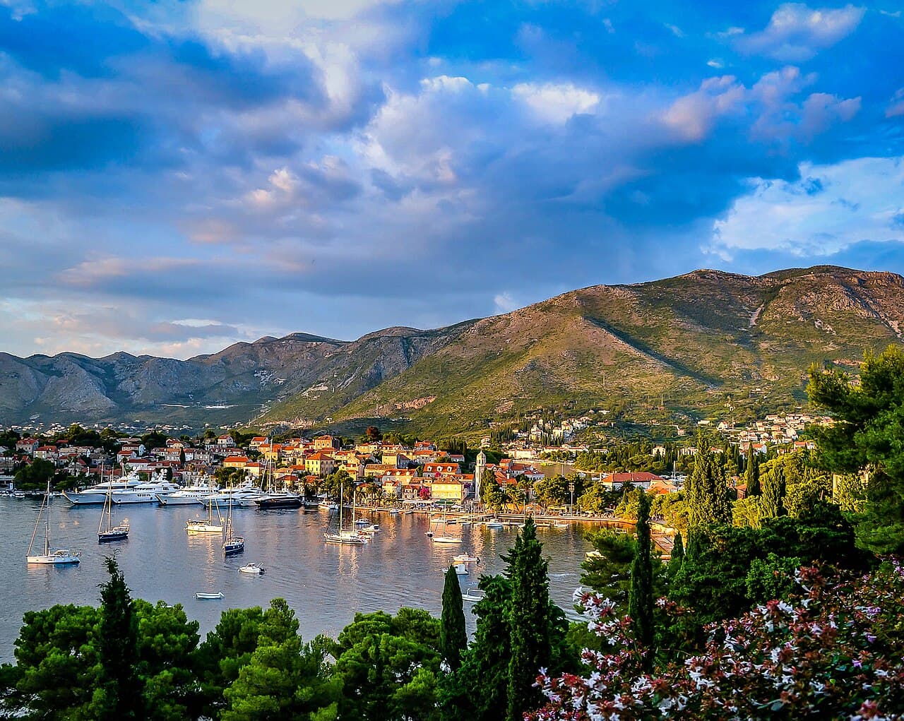 Harbour and waterfront of Cavtat at sunset, with sailing boats and hills behind